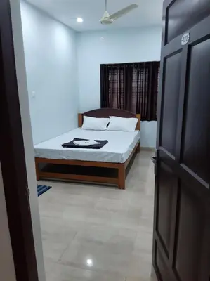 a bedroom with a bed and a open door at MADAPARAMBIL RESIDENCY in Alwaye