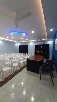 a conference room with white chairs and a wooden table at MADAPARAMBIL RESIDENCY in Alwaye