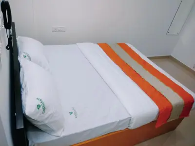 a bed with white sheets and an orange blanket at GREEN LINE RESIDENCY in Nedumbassery