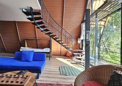 a living room with a blue couch and a staircase at Wild root stay- Orchid Chalet in Vythiri