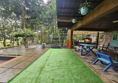 a patio with green grass and picnic tables and benches at Wild root stay- Orchid Chalet in Vythiri