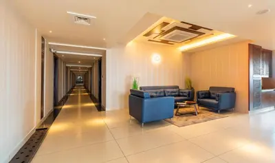 a lobby with two blue chairs and a hallway at Hotel M Pro Palace Mysore - 12 Minutes to Mysore Palace in Mysore