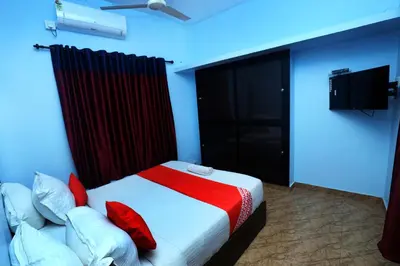 a bedroom with a bed with red pillows and a tv at NARMADA HOMESTAY Ganga in Perintalmanna