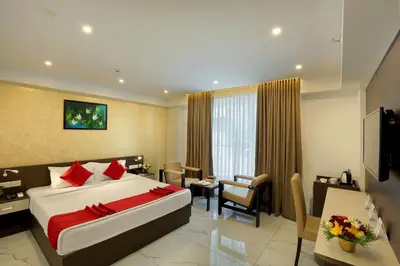 a hotel room with a large bed and a desk at Renai Sreekrishna in Guruvāyūr