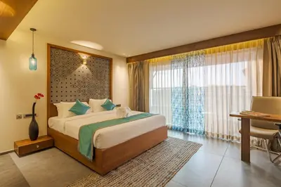 a bedroom with a bed and a desk and a window at GRANDE IRIS in Sultan Bathery