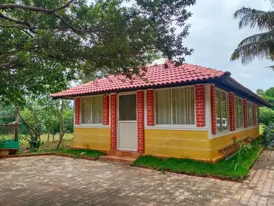 a small yellow house with a red roof at KABINI FARM STAY in Antarasante