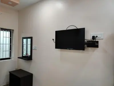a flat screen tv on a white wall in a room at Sivamurugan residency in Bhavāni