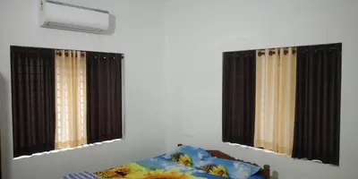 two windows in a room with a bed and a mirror at Pearl Inn in Kottakkal