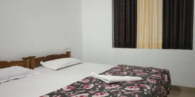 a bedroom with two beds with white sheets and a window at Pearl Inn in Kottakkal