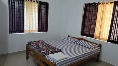 a bed sitting in a room with two windows at Pearl Inn in Kottakkal