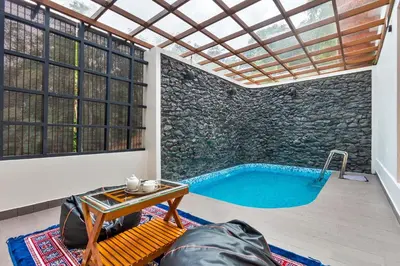 a pool in a room with a stone wall at Serene Valley Resort Wayanad in Mananthavady