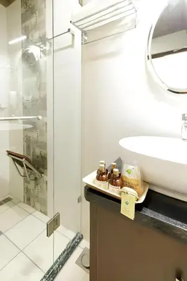 a bathroom with a sink and a glass shower at Lhasa Ayurveda and Wellness Resort - A BluSalzz Collection, Kochi, Kerala in Cochin