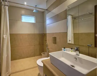 a bathroom with a sink and a toilet and a mirror at Tea Garden Riverside in Munnar
