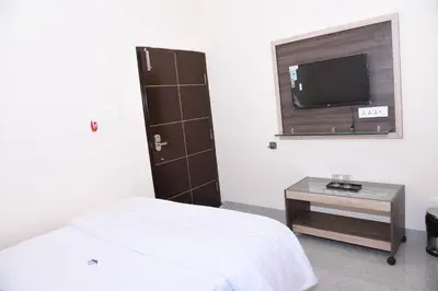 a bedroom with a bed and a tv and a table at Yashas Paradise in Nanjangūd