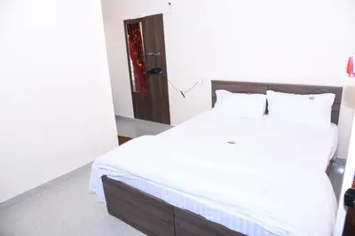 a bedroom with a large bed with white sheets at Yashas Paradise in Nanjangūd