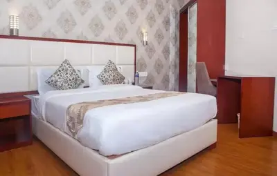 a bedroom with a large white bed with pillows at Hillcrest Metro in Ooty