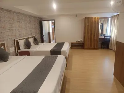 a hotel room with two beds and a hallway at Hillcrest Metro in Ooty