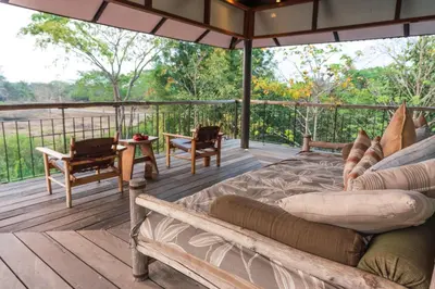 a porch with a bed and a table and chairs at Kaav Safari Lodge, Kabini in Begūr