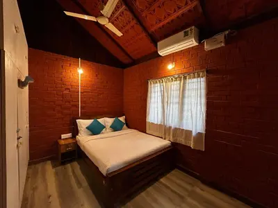 a small bedroom with a bed in a brick wall at Avadale Wayanad - Stag Groups Not Allowed in Kalpetta