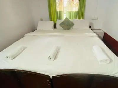 a large bed with white sheets and towels on it at Coorg Daffodil Guesthouse in Madikeri