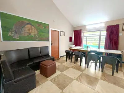 a living room with a couch and a table and chairs at QUEENS COTTAGE - individual cottage in Ooty