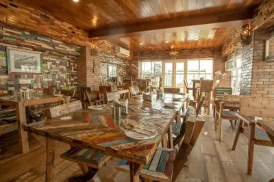 a dining room with a large wooden table and chairs at State Beach Resort And Spa in Kannur