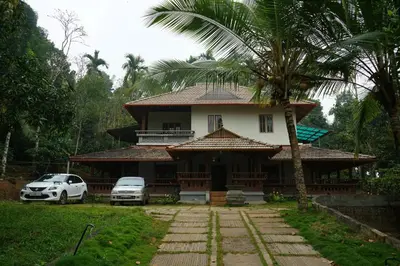 a house with a palm tree in front of it at Wayal Wayanad Heritage villa in Panamaram