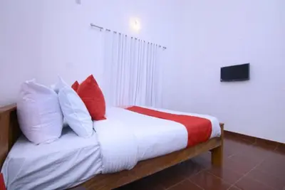 a bed with red and white pillows in a room at Wayal Wayanad Heritage villa in Panamaram