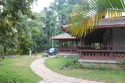a man standing outside of a house with a building at Wayal Wayanad Twin Villa in Panamaram