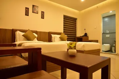 a hotel room with two beds and a table at WHITE SUITE HOTEL in Kozhikode