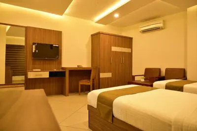 a hotel room with two beds and a flat screen tv at WHITE SUITE HOTEL in Kozhikode