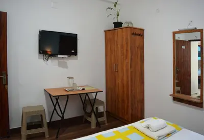a bedroom with a bed and a table and a tv at EDEN Paradisee in Ooty