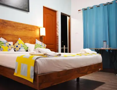 a bedroom with a large bed with blue curtains at EDEN Paradisee in Ooty