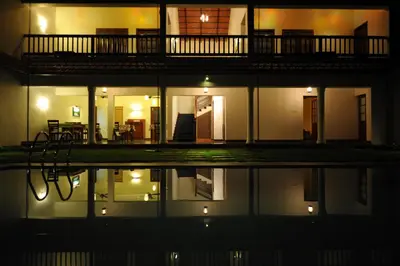 a house at night with its reflection in the water at The Villa Romantica in Nedumbassery