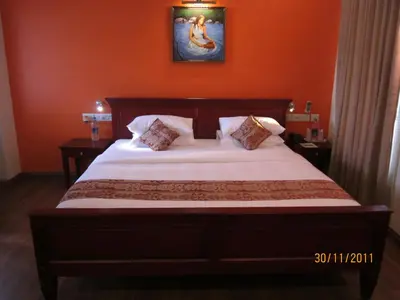 a bedroom with a large bed with an orange wall at The Villa Romantica in Nedumbassery