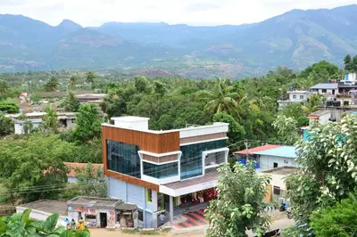a building in a town with mountains in the background at Hotel Magnet in Marayoor