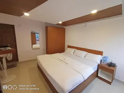 a bedroom with a large white bed in a room at Hotel Magnet in Marayoor