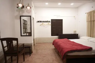 a bedroom with a bed and a desk and a chair at Kayyalas Courtyard in Trichūr