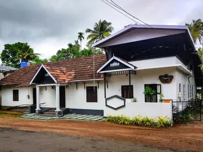 a white house with a brown roof at Kayyalas Courtyard in Trichūr