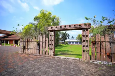 a wooden gate with a fence and a field at Clay House in Trichūr