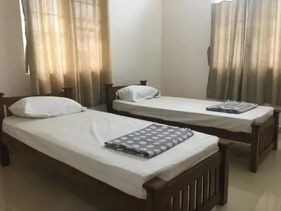 two twin beds in a room with curtains at Shantham Service Apartments, Kinathukadavu, Coimbatore in Coimbatore