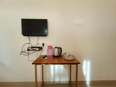 a small table with a television on a white wall at Shantham Service Apartments, Kinathukadavu, Coimbatore in Coimbatore