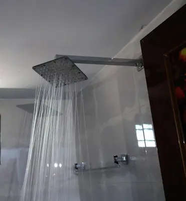 a shower with white curtains in a bathroom at NARMADA HOMESTAY Yamuna in Malappuram