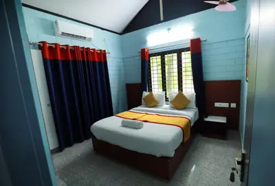 a bedroom with a bed with red and blue curtains at NARMADA HOMESTAY Yamuna in Malappuram
