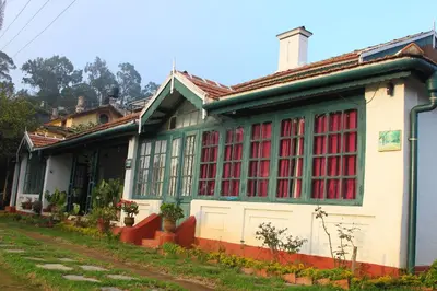 a house with red and green windows on a street at HS Holiday Home in Coonoor