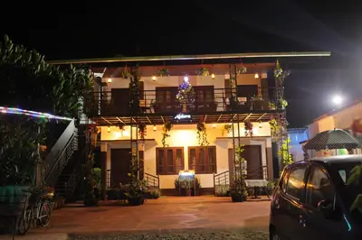 a white house with a balcony at night at Aldora Holiday Homes in Vythiri