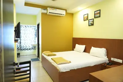 a bedroom with a bed and a desk and a window at Sri Krishnan Residency in Pollāchi