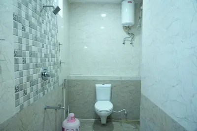 a bathroom with a white toilet in a shower at Sri Krishnan Residency in Pollāchi