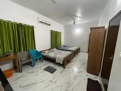 a room with a bed and a table and a chair at Jayuz Homestay & Foodies in Kozhikode