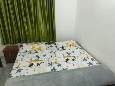 a bed with a comforter on it in a bedroom at Jayuz Homestay & Foodies in Kozhikode